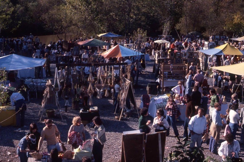 the crowd shops at booths along the creek.